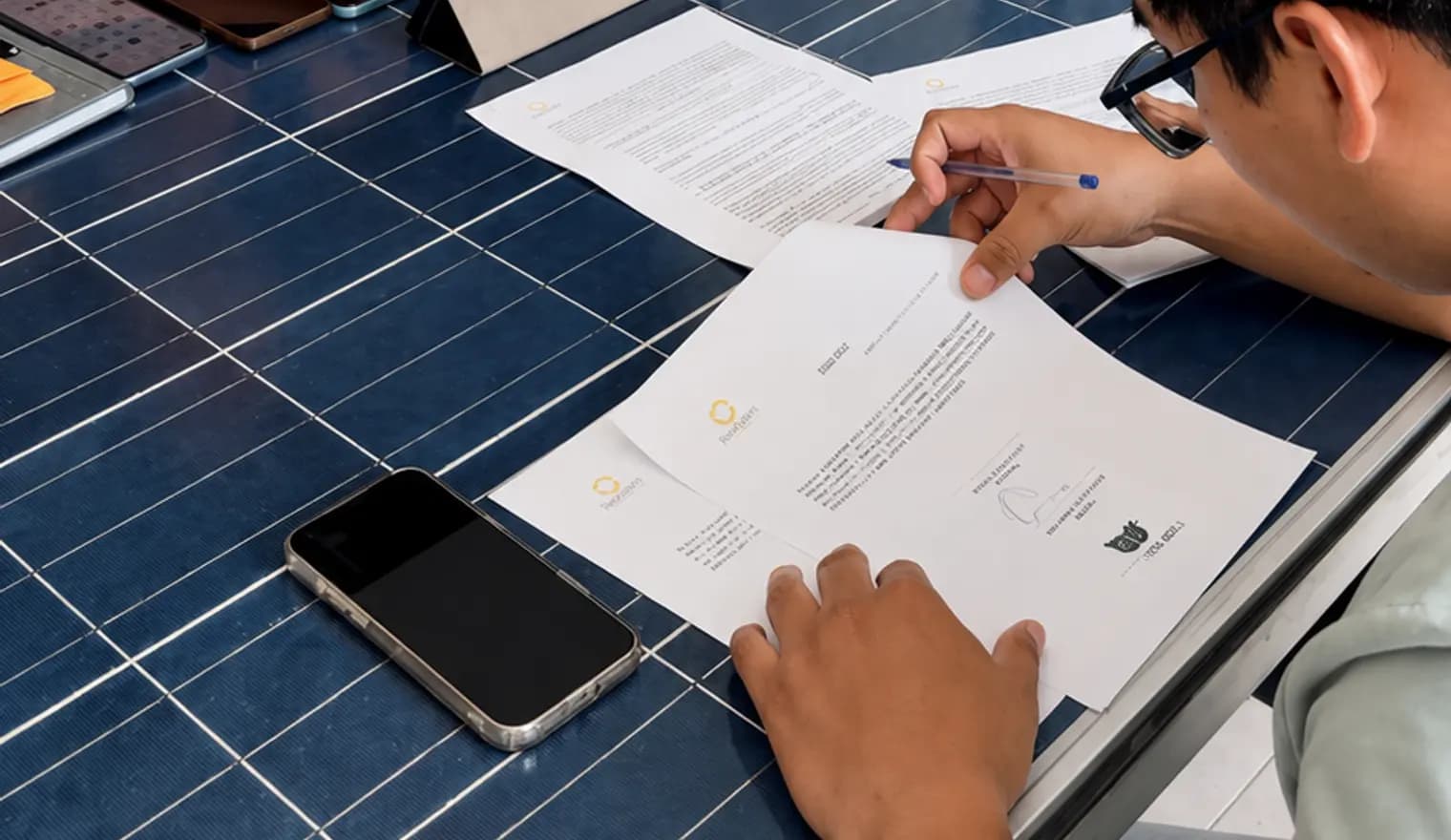 Firma de un contrato de Reciclasol sobre una mesa hecha de paneles solares